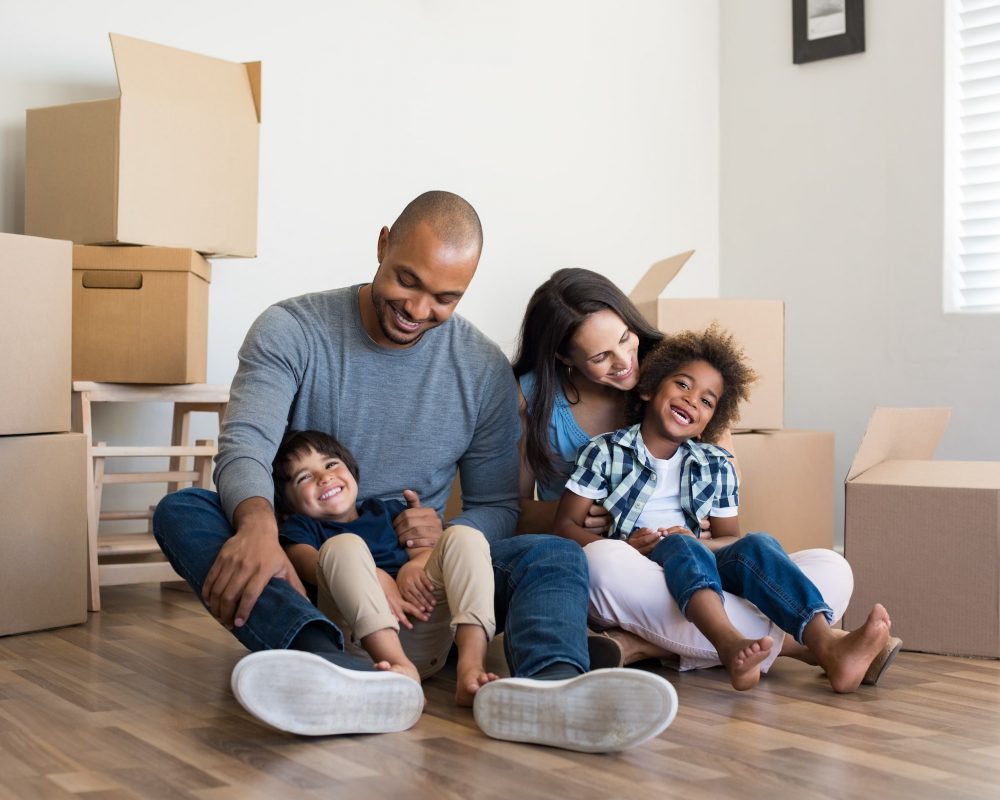 Family together on floor while moving with boxes in background